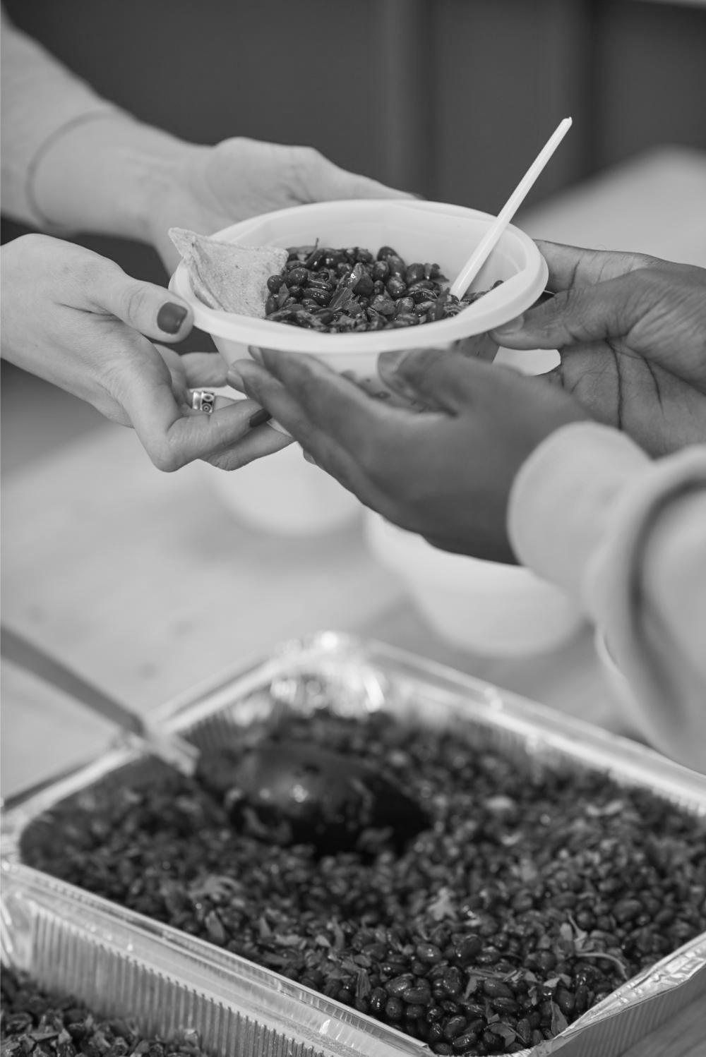 Volunteers handing over a bowl of food, illustrative photograph